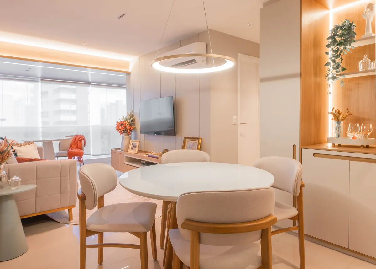 Sala de jantar e estar do Apartamento Blue, com mesa redonda, pendente em anel e nicho de madeira iluminado